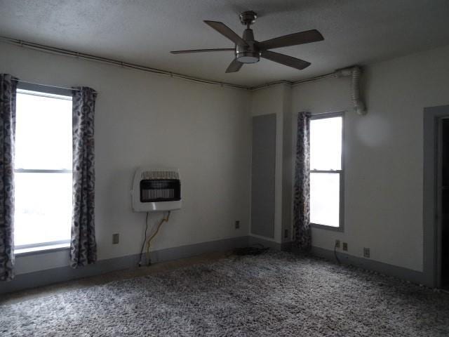 spare room featuring carpet flooring, a textured ceiling, heating unit, and ceiling fan