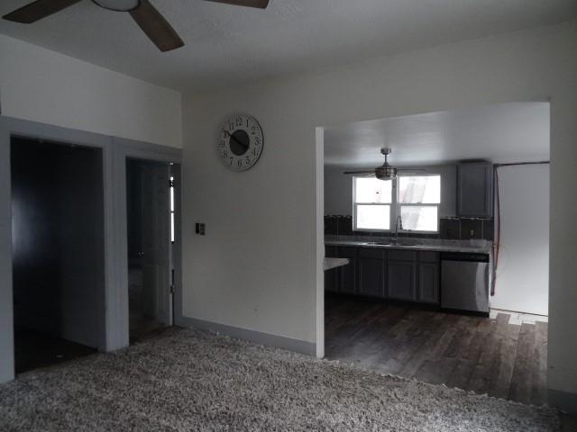 interior space featuring a ceiling fan, dark wood-style flooring, dishwasher, and a sink