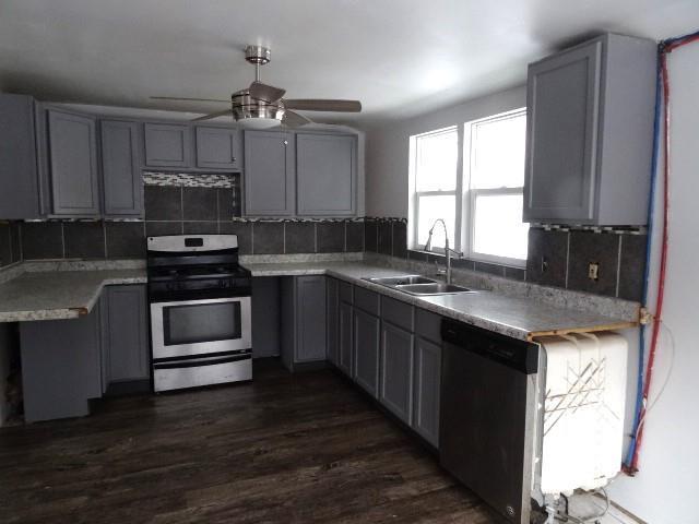 kitchen featuring appliances with stainless steel finishes, backsplash, gray cabinetry, ceiling fan, and sink