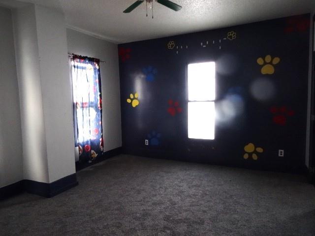 carpeted empty room featuring ceiling fan and a textured ceiling