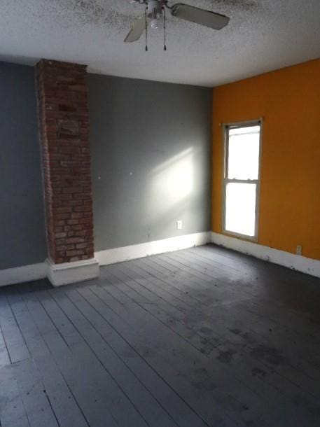 empty room with ceiling fan, wood-type flooring, and a textured ceiling