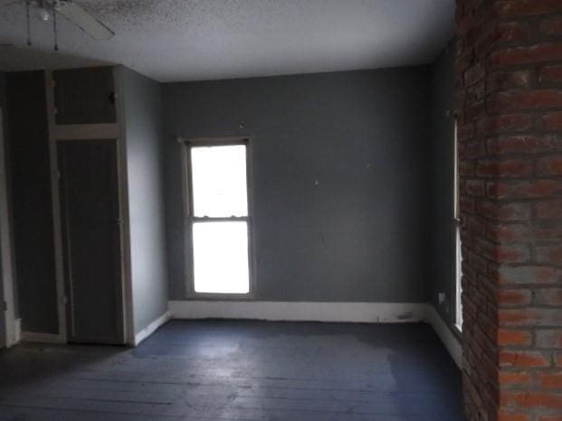 unfurnished room featuring a textured ceiling, dark hardwood / wood-style floors, and ceiling fan