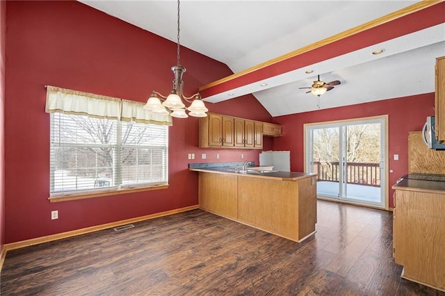 kitchen with kitchen peninsula, dark wood-type flooring, lofted ceiling, hanging light fixtures, and ceiling fan with notable chandelier