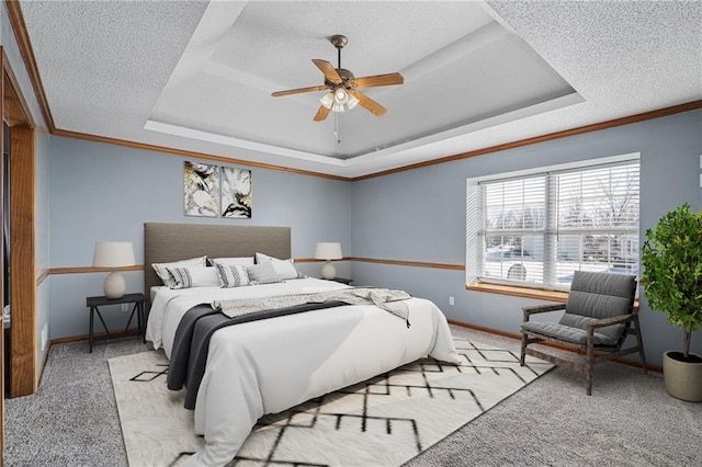 carpeted bedroom with a textured ceiling, ceiling fan, and a tray ceiling