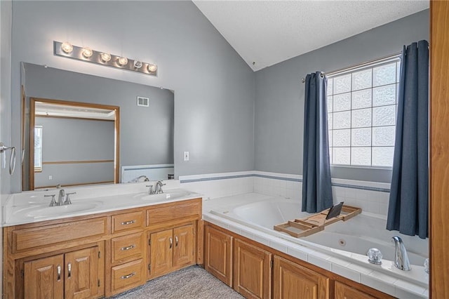 bathroom featuring lofted ceiling, vanity, a bathing tub, and a textured ceiling