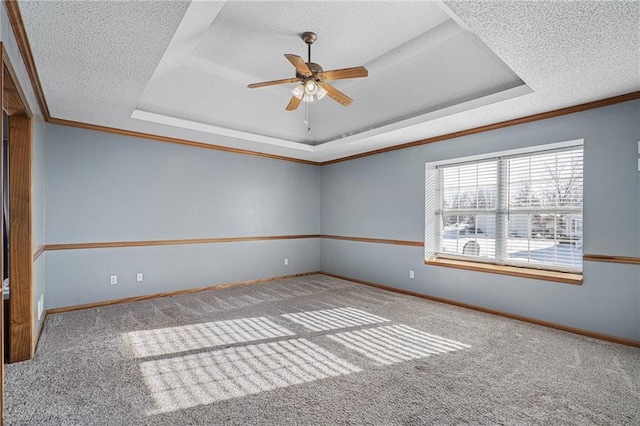 carpeted empty room featuring ceiling fan, a textured ceiling, crown molding, and a raised ceiling