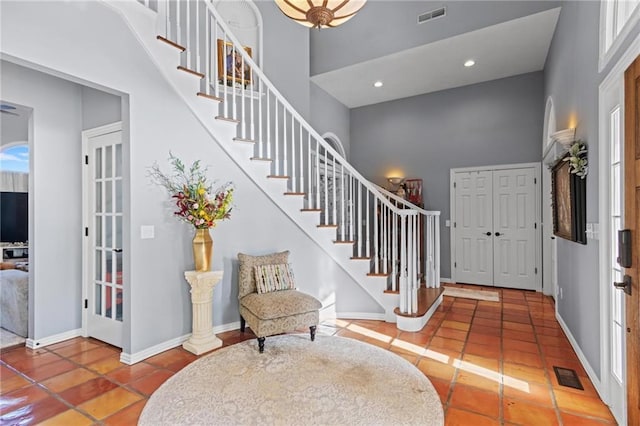 tiled foyer featuring french doors, a towering ceiling, and plenty of natural light