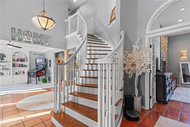 stairs with tile patterned flooring, built in shelves, and ceiling fan