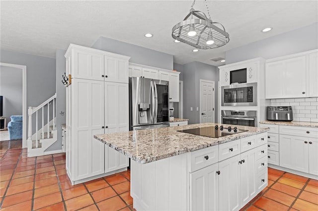 kitchen featuring a center island, light tile patterned floors, pendant lighting, white cabinets, and appliances with stainless steel finishes