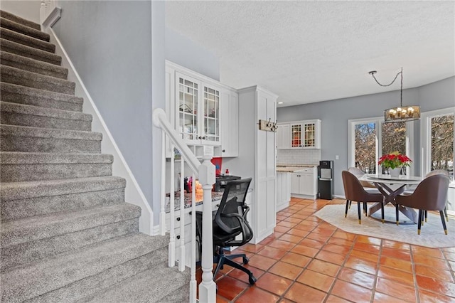 stairway with a chandelier, a textured ceiling, and tile patterned floors