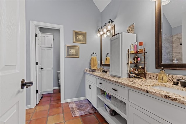 bathroom featuring tile patterned flooring, vanity, toilet, and lofted ceiling