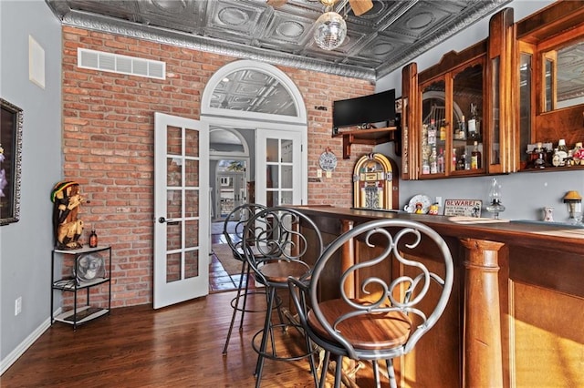 bar featuring french doors, dark wood-type flooring, and brick wall