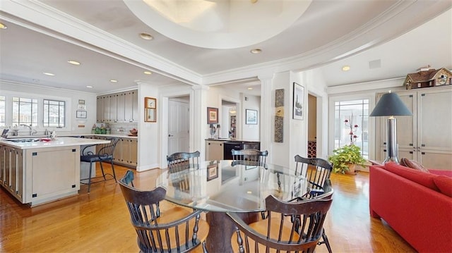 dining space with sink, light wood-type flooring, and crown molding