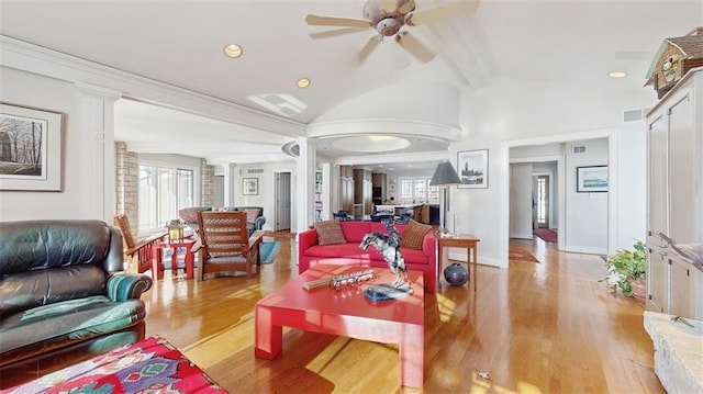 living room featuring a healthy amount of sunlight, light hardwood / wood-style flooring, lofted ceiling with beams, and ornate columns