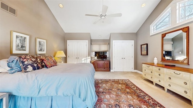 carpeted bedroom with high vaulted ceiling, two closets, and ceiling fan