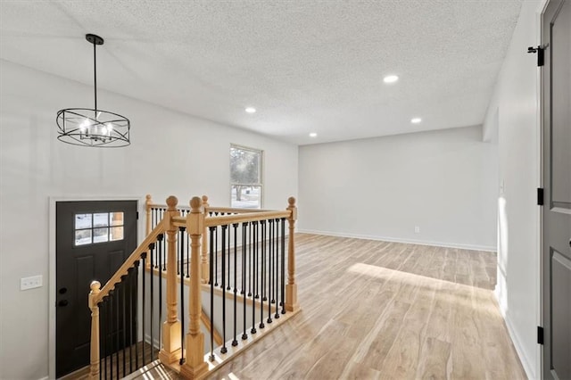 interior space with a textured ceiling, a chandelier, and light wood-type flooring