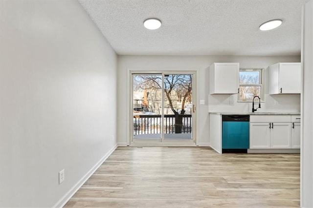 unfurnished dining area with a textured ceiling, light wood-type flooring, and a healthy amount of sunlight