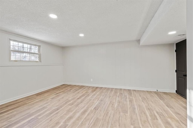 basement with light hardwood / wood-style floors and a textured ceiling