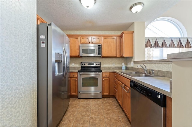 kitchen with light tile patterned floors, a textured ceiling, stainless steel appliances, and sink