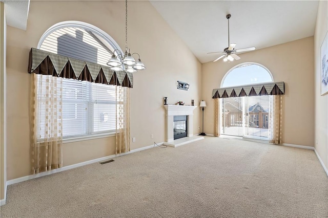 unfurnished living room featuring carpet flooring, high vaulted ceiling, and ceiling fan with notable chandelier