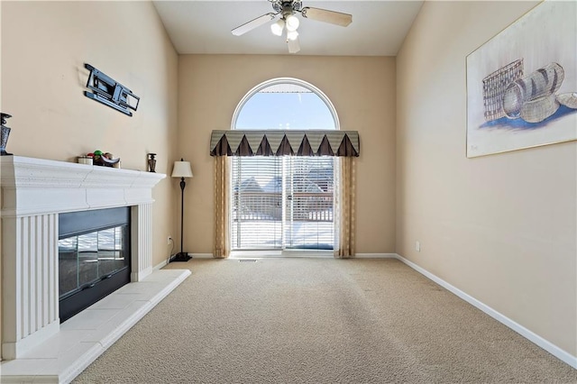 unfurnished living room with ceiling fan, light colored carpet, and a tiled fireplace