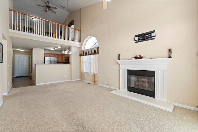 unfurnished living room featuring ceiling fan, high vaulted ceiling, and light carpet