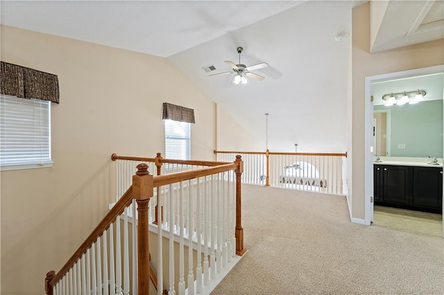 corridor featuring light carpet, vaulted ceiling, and sink