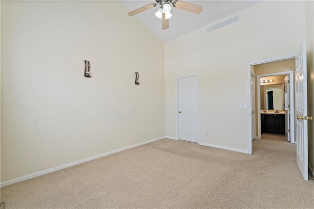 unfurnished bedroom with a closet, light colored carpet, high vaulted ceiling, and ceiling fan