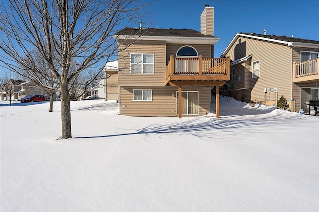 snow covered back of property with a deck