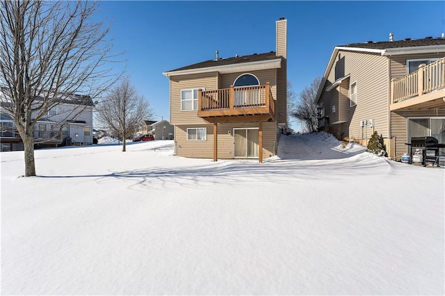 snow covered rear of property with a balcony