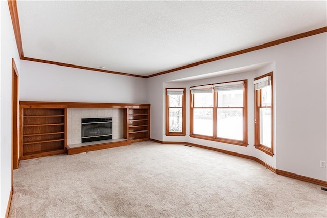 unfurnished living room with carpet, baseboards, ornamental molding, and a tile fireplace