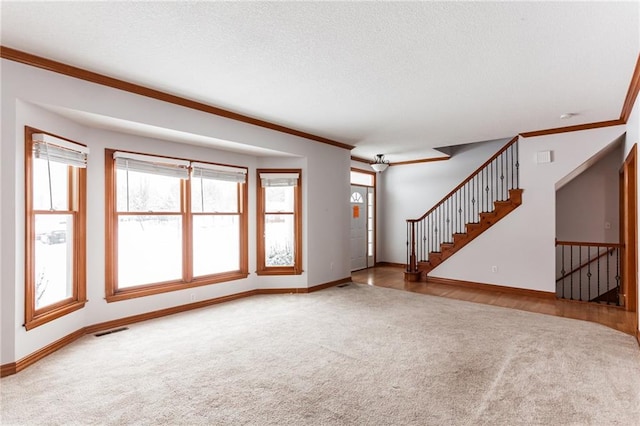 unfurnished living room featuring carpet, crown molding, visible vents, baseboards, and stairs