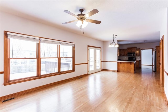 unfurnished living room with light wood finished floors, baseboards, visible vents, ceiling fan, and french doors