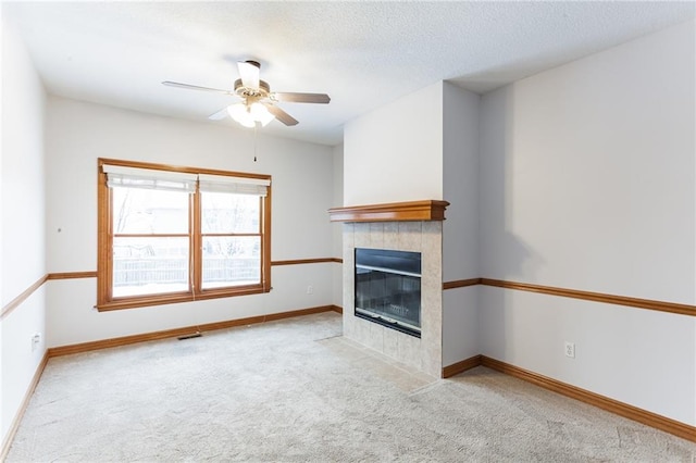 unfurnished living room with carpet, baseboards, visible vents, and a tiled fireplace