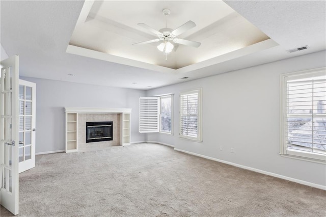 unfurnished living room with carpet, a raised ceiling, and visible vents