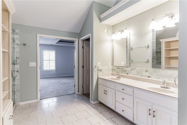 full bathroom with lofted ceiling, double vanity, a sink, and a tile shower