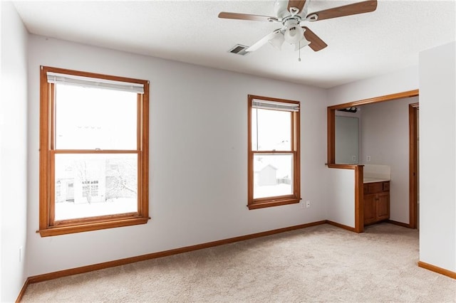 unfurnished bedroom with light carpet, a ceiling fan, visible vents, and baseboards