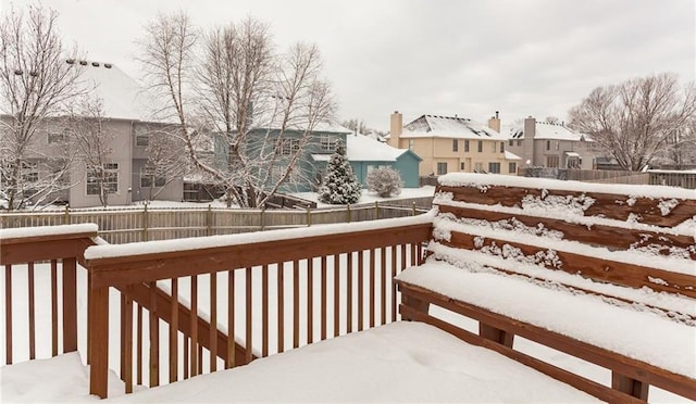 snow covered deck with a residential view and fence