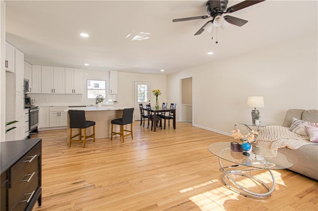 living room with ceiling fan and light hardwood / wood-style floors