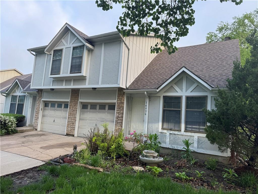 14936-14938 W Riggs St, Overland Park, KS 66223 - view of front facade featuring roof with shingles, an attached garage, stone siding, board and batten siding, and driveway