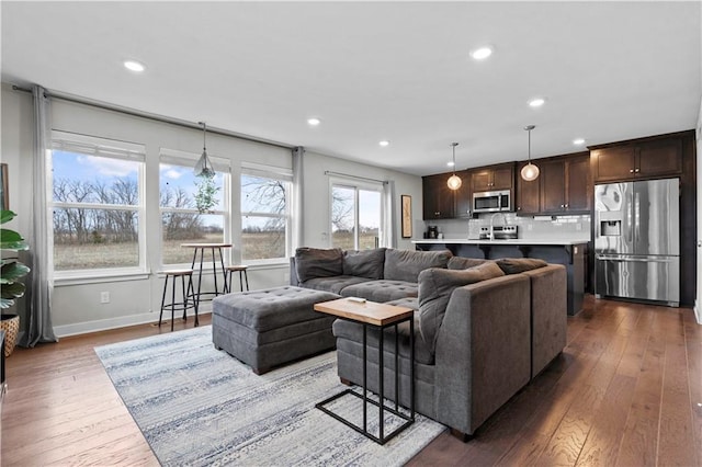 living area with baseboards, dark wood finished floors, and recessed lighting