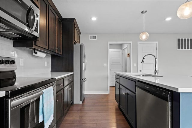 kitchen with stainless steel appliances, a sink, visible vents, light countertops, and pendant lighting