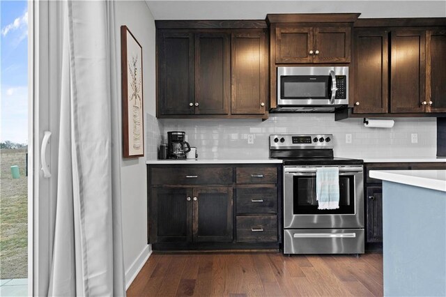 kitchen with tasteful backsplash, dark wood-style floors, stainless steel appliances, dark brown cabinets, and light countertops