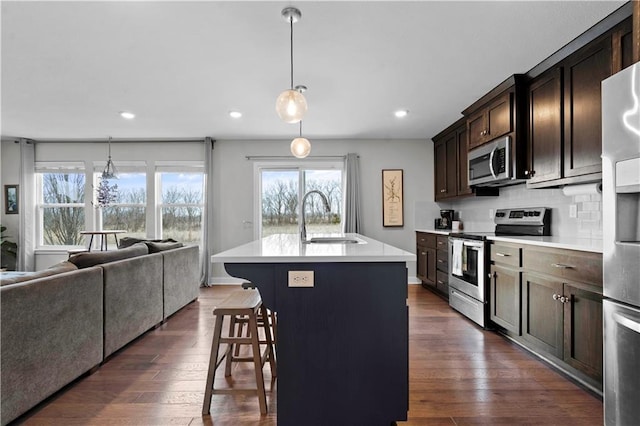 kitchen with a sink, stainless steel appliances, an island with sink, and light countertops