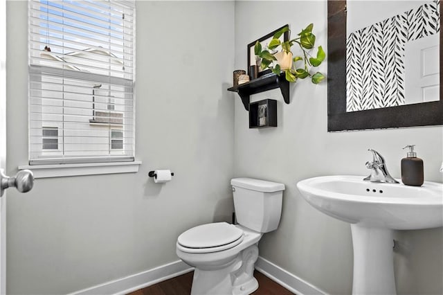 half bath with wood finished floors, toilet, and baseboards