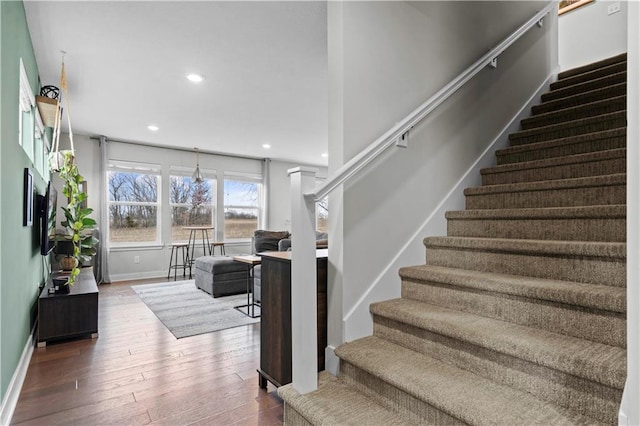 stairway with baseboards, wood finished floors, and recessed lighting