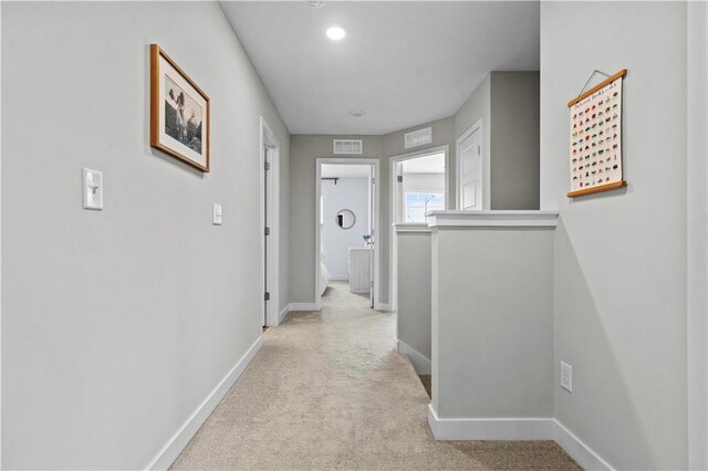 hall featuring light carpet, visible vents, and baseboards