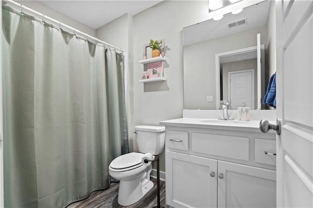 bathroom with toilet, wood finished floors, vanity, and visible vents