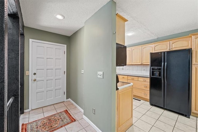 kitchen featuring tasteful backsplash, light tile patterned flooring, black fridge with ice dispenser, a textured ceiling, and light brown cabinetry