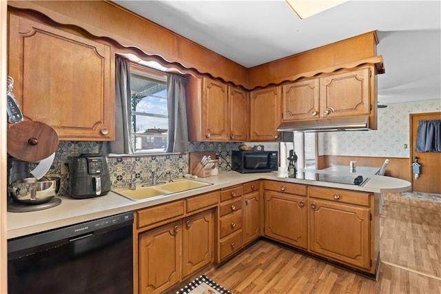 kitchen with sink, black appliances, light hardwood / wood-style flooring, and kitchen peninsula